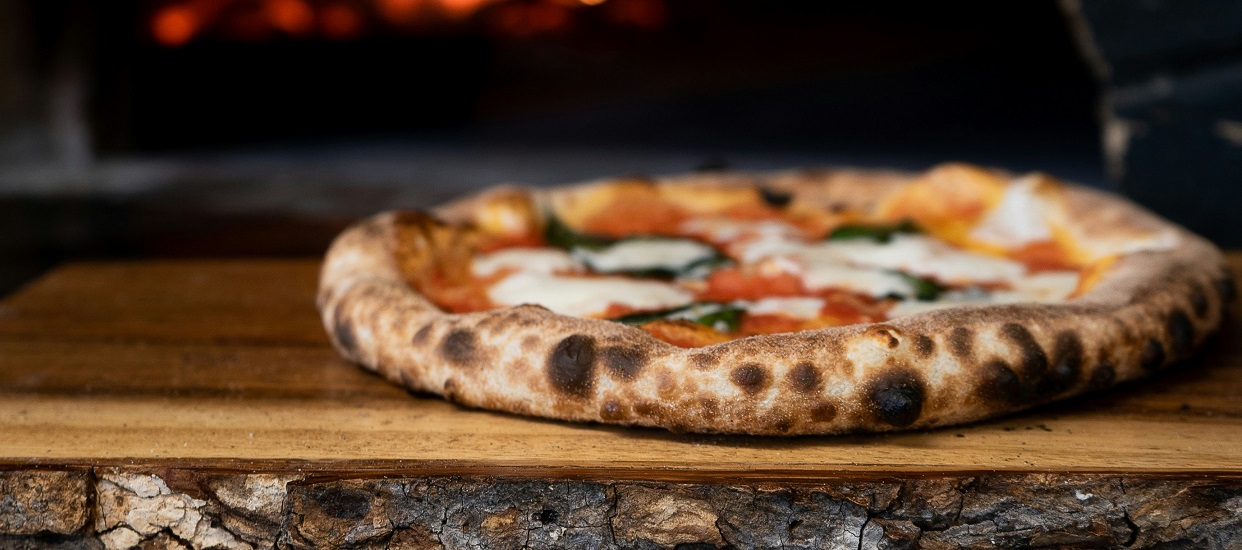 Stonebaked pizza on wood by stove