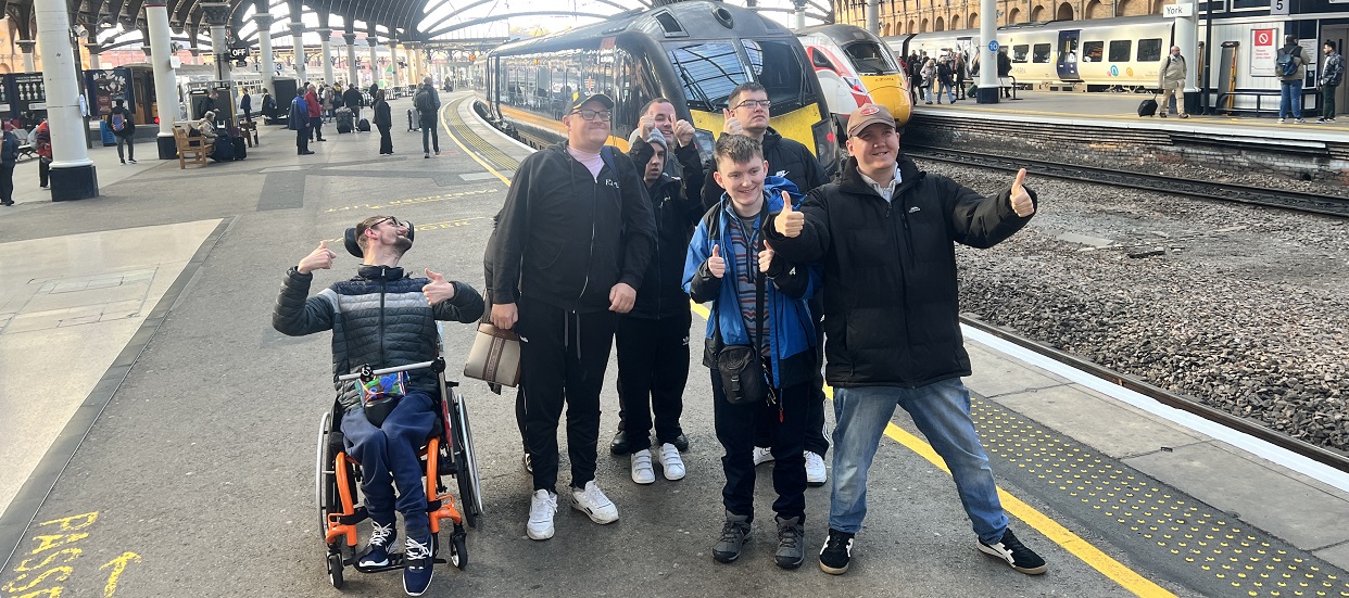 Students smiling for a photo in front of a Grand Central train at York station
