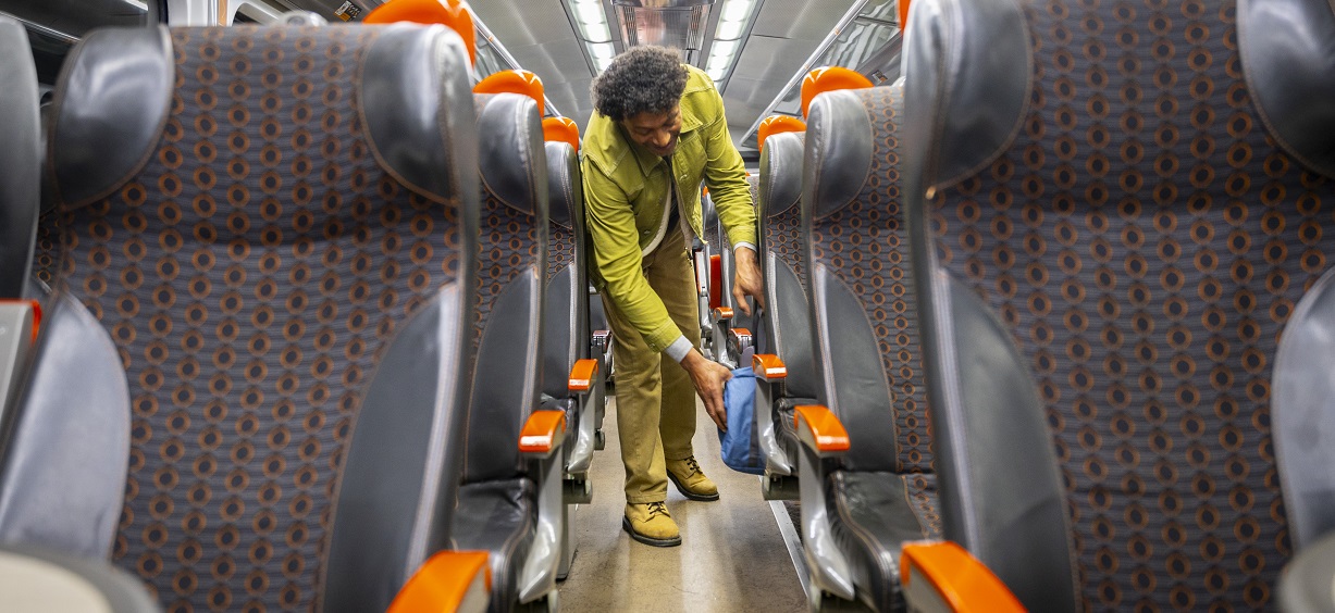 man storing his backpack on board a Grand Central train